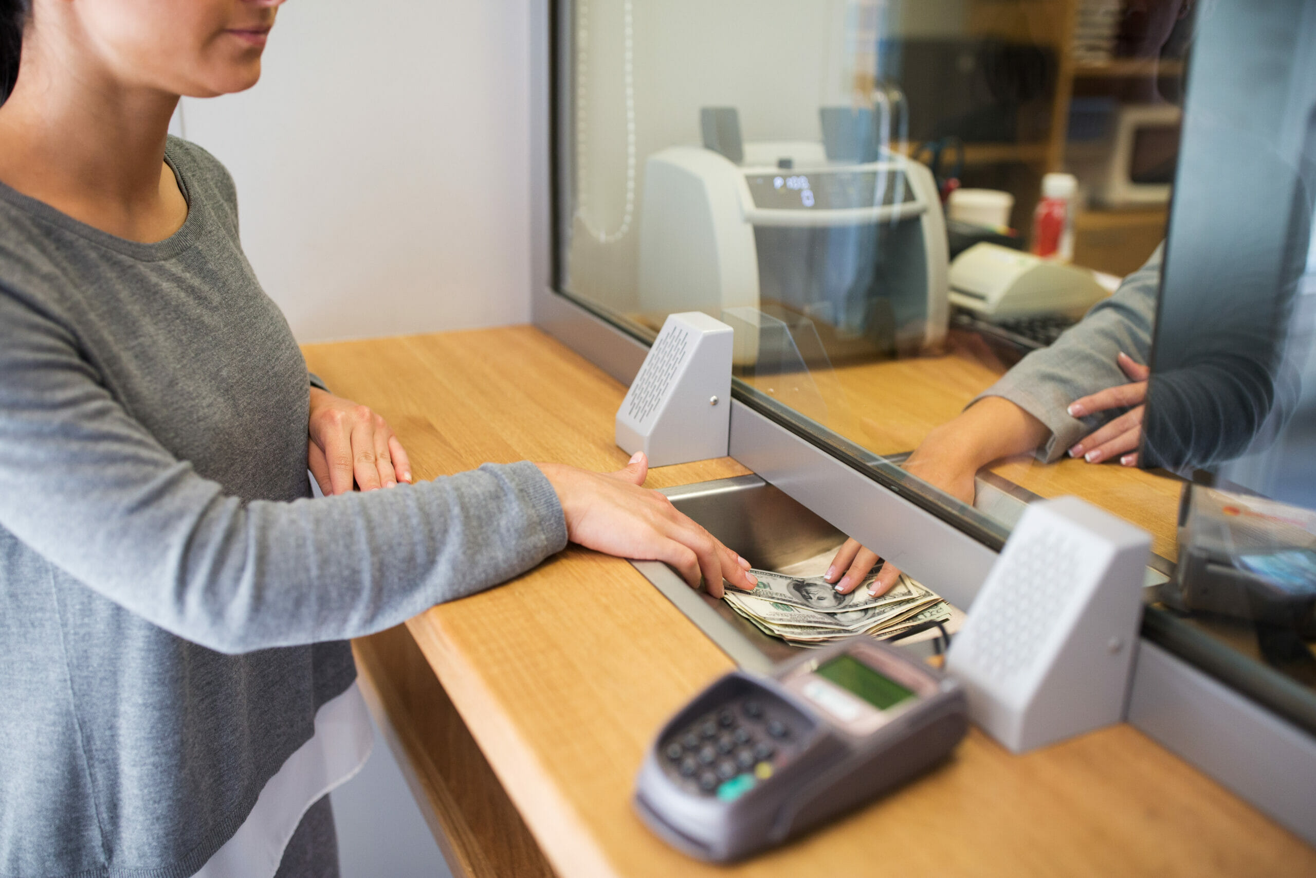 Immigrant woman deposits cash at a bank. 