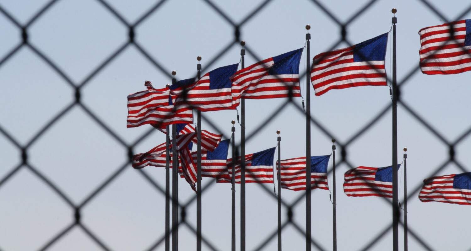 US flags behind chainlink fence