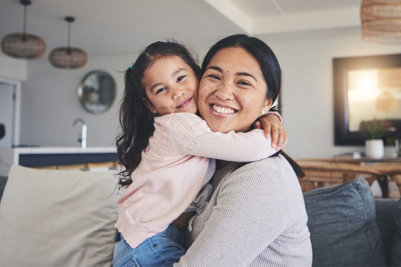 happy and portrait of mother and daughter on sofa for love, care and support. Smile, calm and relax with woman and young girl embrace in living room of family home for peace, cute and bonding